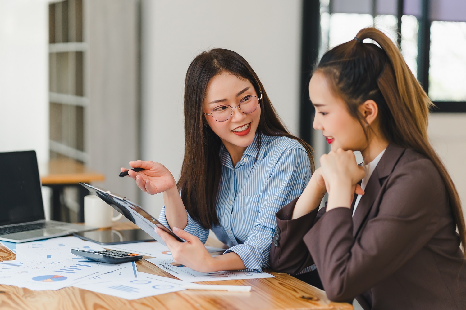 Two,Engaged,Asian,Female,Colleagues,Discussing,Project,Details,On,A